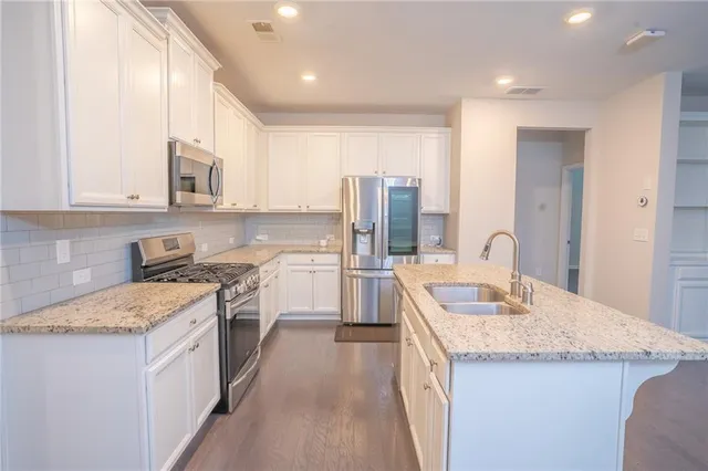 a kitchen with a sink stove a refrigerator and white cabinets