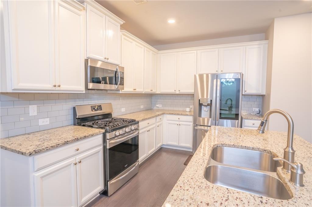 2420 Boxwalking Court Cumming, GA 30040 - Photo 8 of 42 a kitchen with stainless steel appliances granite countertop a sink stove and refrigerator