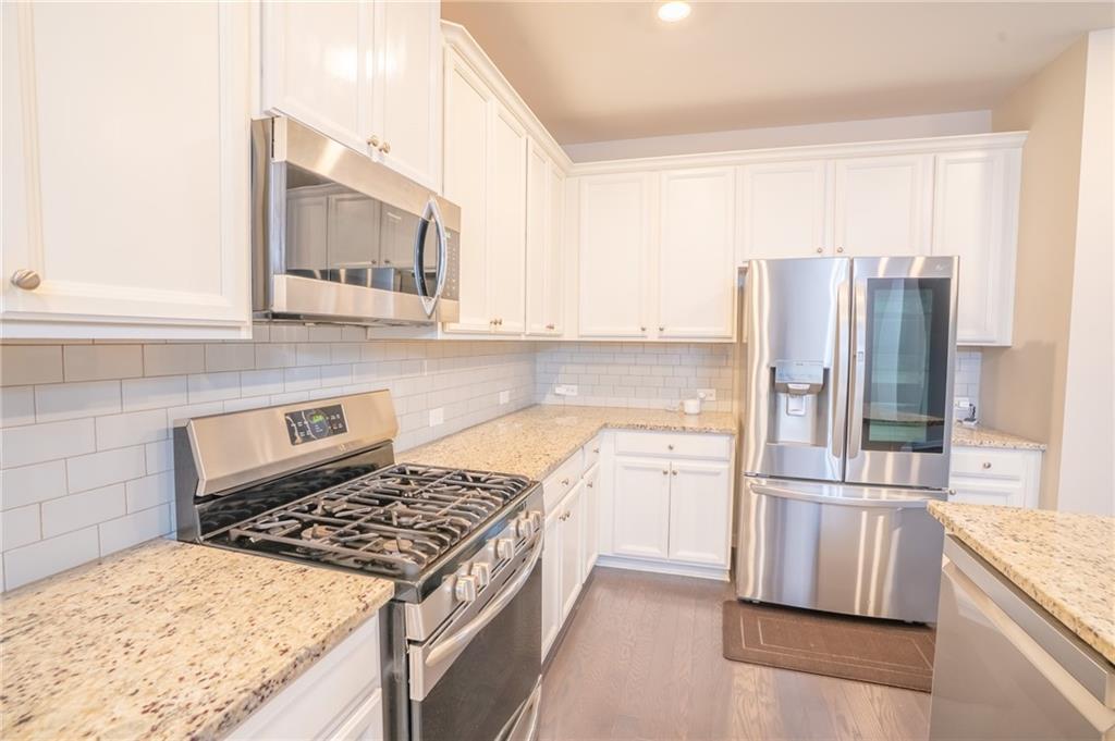 2420 Boxwalking Court Cumming, GA 30040 - Photo 9 of 42 a kitchen with stainless steel appliances granite countertop a stove a sink and a refrigerator
