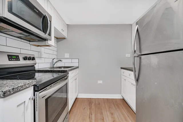 a kitchen with granite countertop cabinets stainless steel appliances and a wooden floor