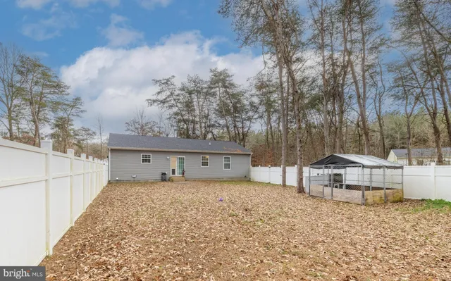 a view of a house with large trees and wooden fence
