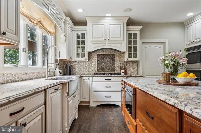 a kitchen with granite countertop a sink stainless steel appliances white cabinets and a window