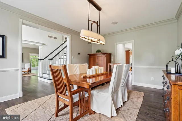 a dining room with wooden floor a chandelier a wooden table and chairs