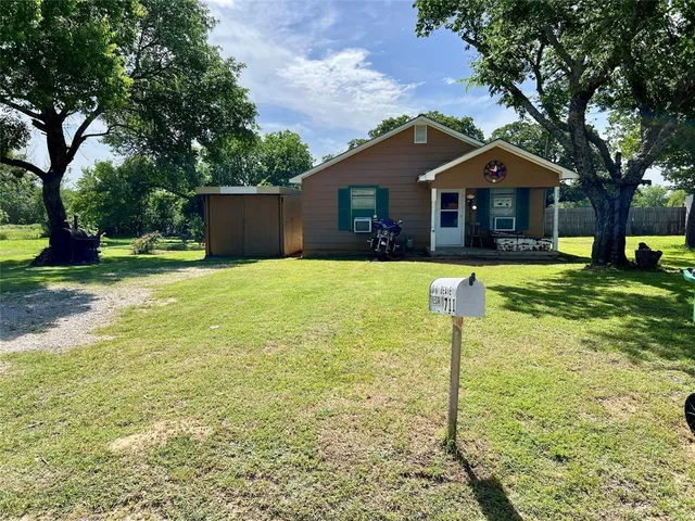 a front view of a house with yard and tree