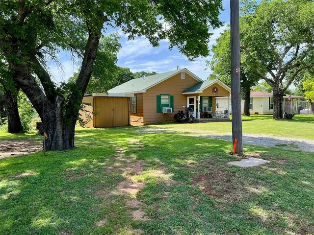 a front view of a house with a yard and trees