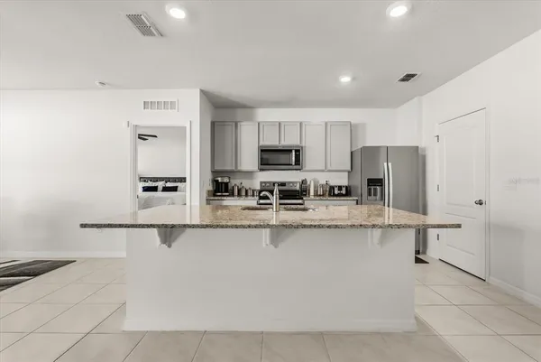 a kitchen with stainless steel appliances granite countertop a refrigerator a stove and a sink