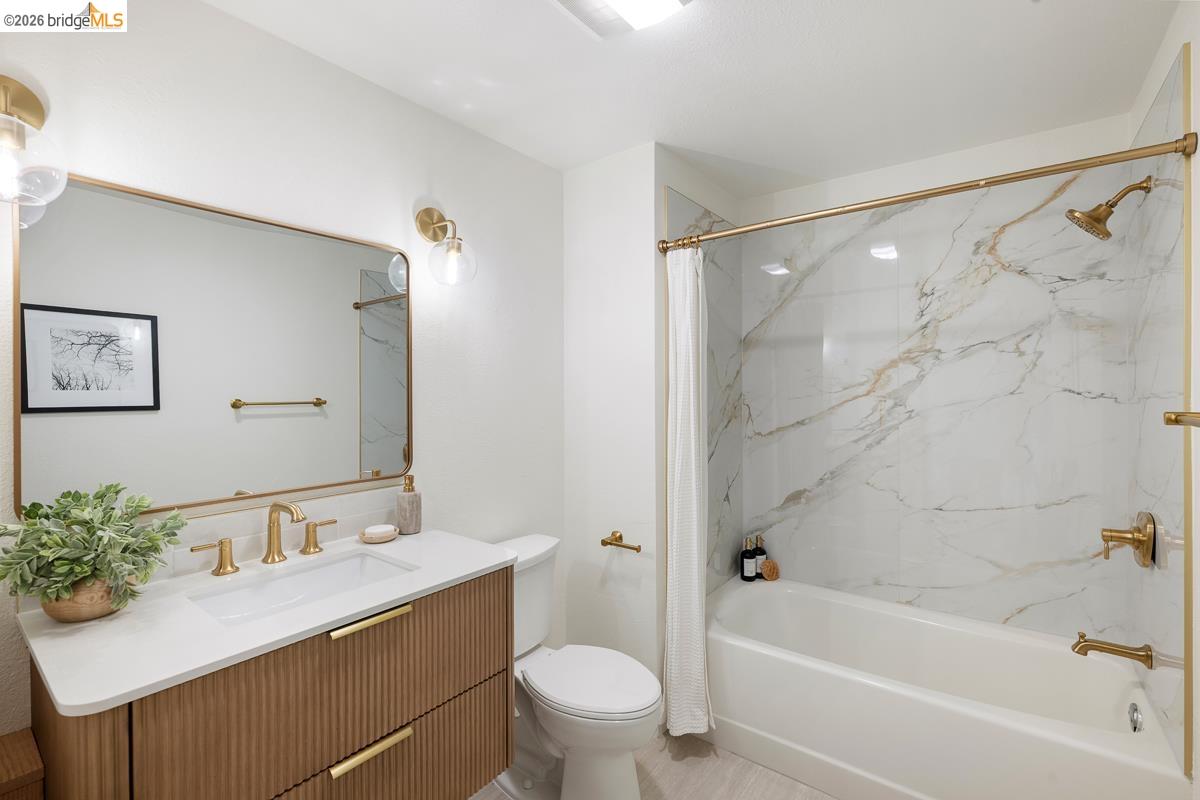 2029 Channing Way, Unit 3D Berkeley, CA 94704 - Photo 36 of 54 Bathroom featuring a white bathtub with a faux marble surround, gold-finish fixtures, and a coordinating gold-framed mirror