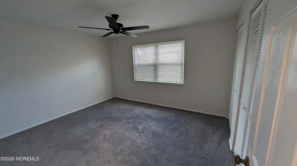 an empty room with closet and a ceiling fan