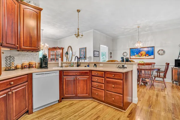 a kitchen with stainless steel appliances granite countertop a sink dishwasher a stove with wooden cabinets and floor