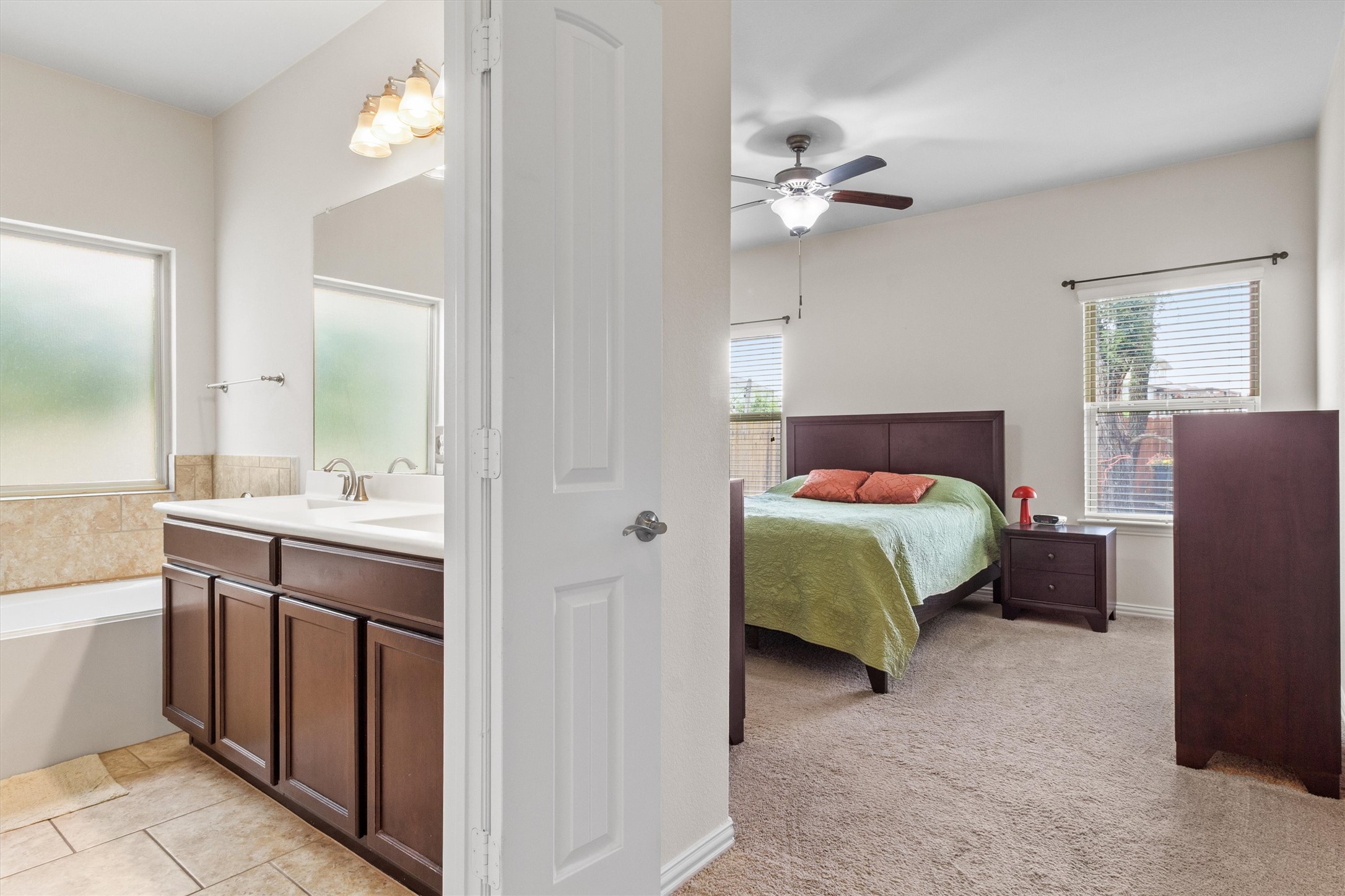 10413 Crescendo Lane Austin, TX 78747 - Photo 13 of 32 The bathroom features a deep soaking tub, dual sinks, and tile flooring, while the bedroom offers carpet and a ceiling fan.