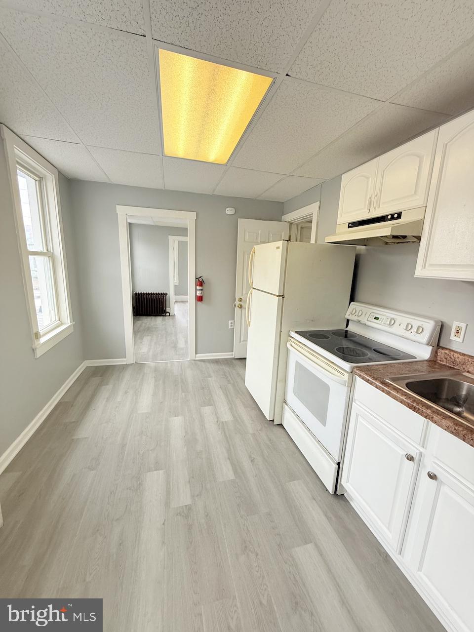 145 Spring Valley Road Reading, PA 19605 - Photo 20 of 44 a kitchen with granite countertop a stove a sink and white cabinets with wooden floor