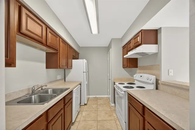 a kitchen with a sink stove top oven and refrigerator