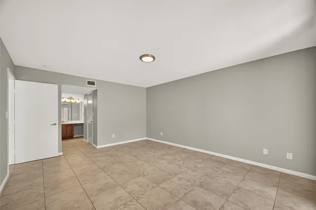a view of an empty room with kitchen and chandelier
