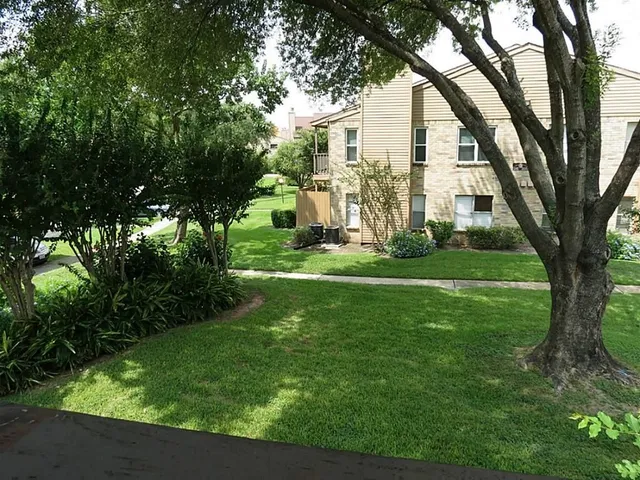 a view of a white house in a big yard with large trees