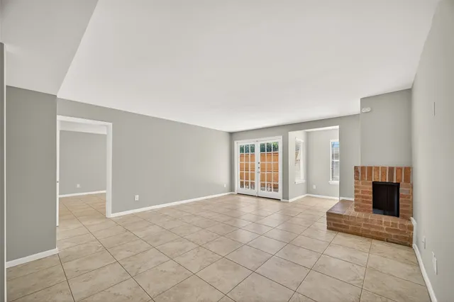 an empty room with windows and fireplace