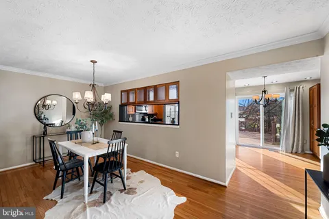 a dining room with wooden floor a chandelier a wooden table and chairs