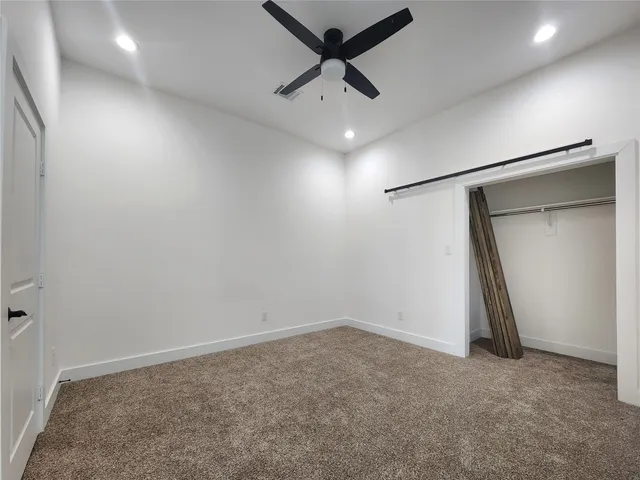 an empty room with a ceiling fan and wooden floor