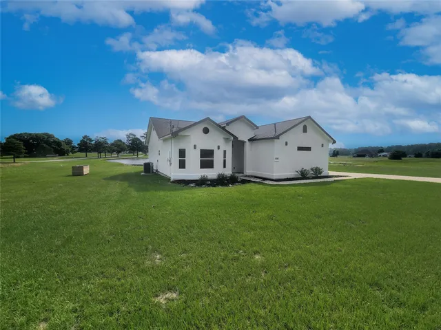 a view of a house with a big yard and large trees