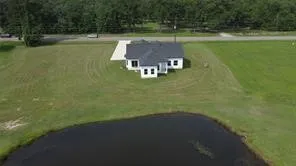 a view of a lake with a yard and large trees