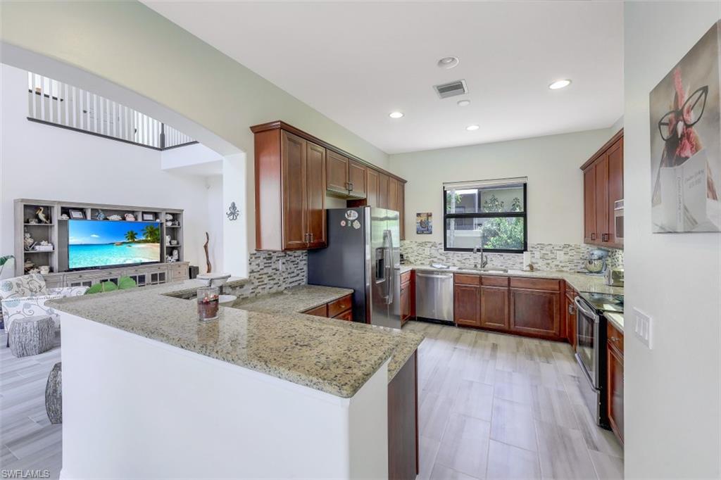 1276 Kendari Terrace Naples, FL 34113 - Photo 12 of 31 a kitchen with stainless steel appliances granite countertop a sink stove and wooden floor