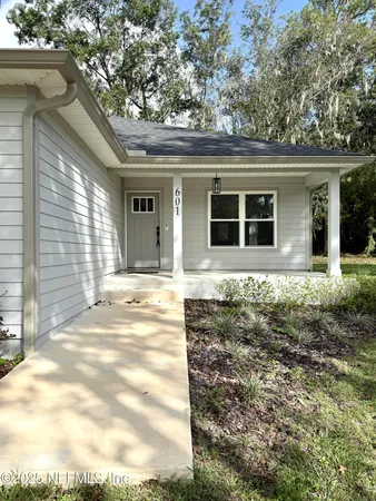 a white house that has a tree in front of a house