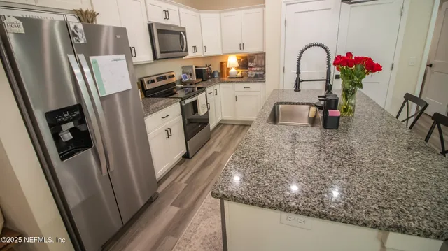 a kitchen with stainless steel appliances granite countertop a refrigerator stove and sink