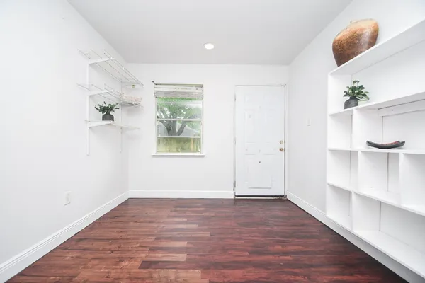 an empty room with wooden floor and windows