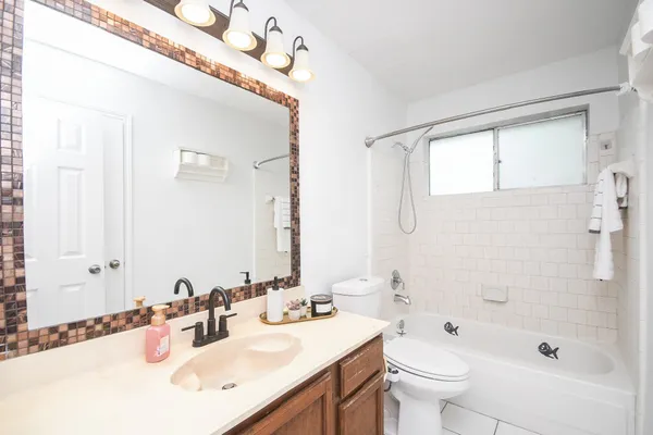 a bathroom with a bathtub shower sink mirror vanity and toilet