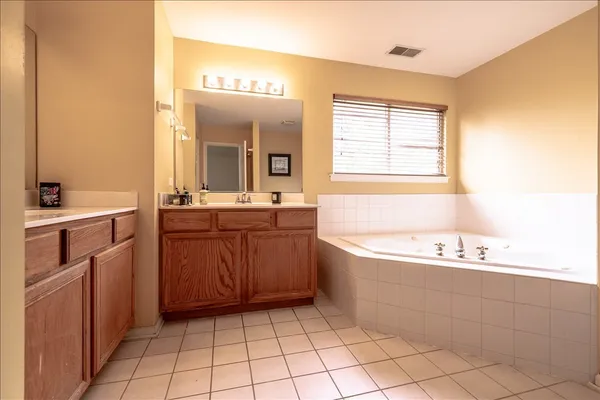 a bathroom with a bathtub a sink a mirror and a bathtub