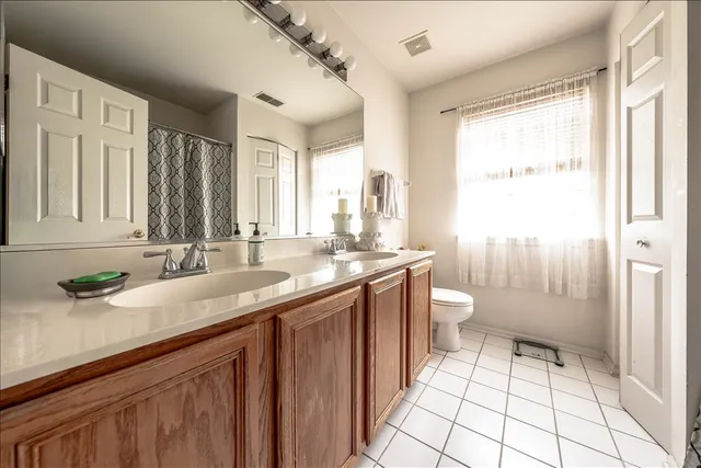 a bathroom with a granite countertop sink a toilet a mirror and shower