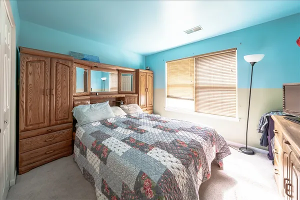 a bedroom with a bed next to a window with closet