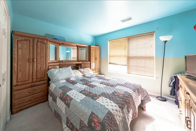 a bedroom with a bed next to a window with closet