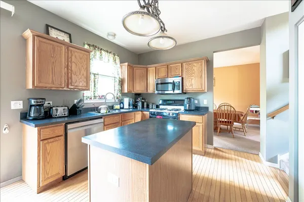 a kitchen with stainless steel appliances granite countertop a stove top oven a sink dishwasher a dining table and chairs with wooden floor