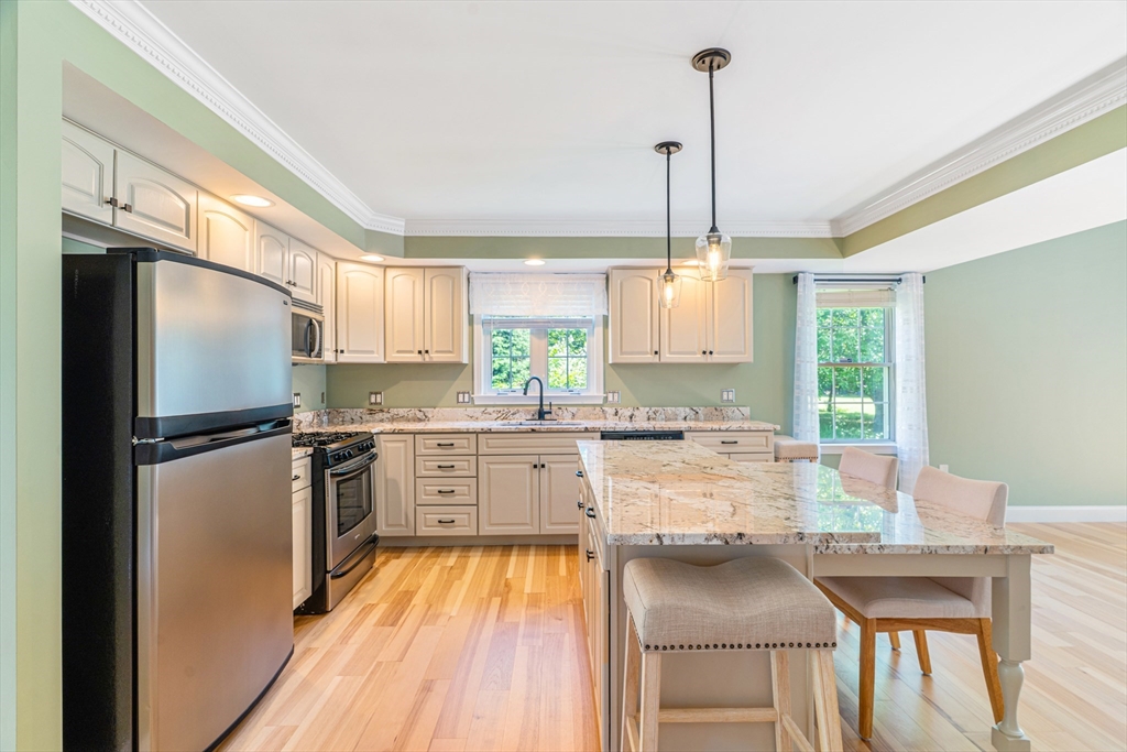 53 Baldwin Road, Unit 1201 Billerica, MA 01821 - Photo 9 of 36 a kitchen with a refrigerator a sink dishwasher a stove and white cabinets with wooden floor