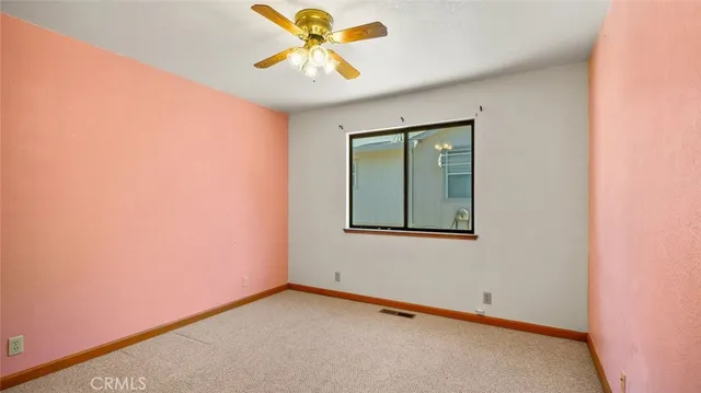 an empty room with a window and ceiling fan