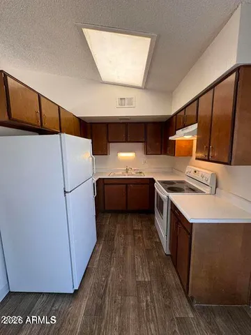 a kitchen with stainless steel appliances a refrigerator a sink and wooden floors
