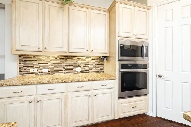 a kitchen with granite countertop white cabinets and stainless steel appliances
