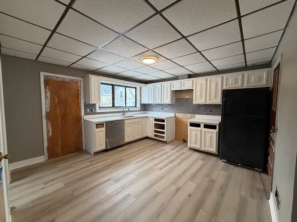 a kitchen with stainless steel appliances granite countertop a stove a refrigerator a sink dishwasher and white cabinets with wooden floor