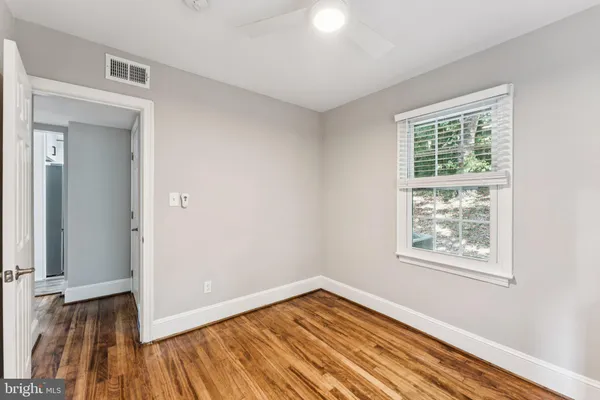 a view of an empty room with wooden floor and a window