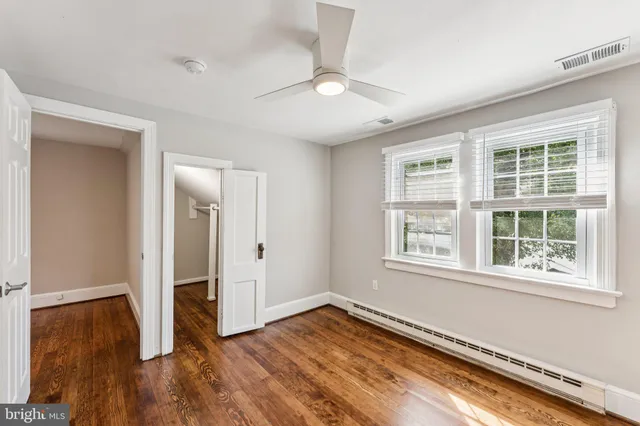 an empty room with wooden floor cabinet and windows