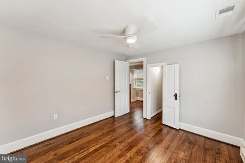 an empty room with wooden floor and ceiling fan