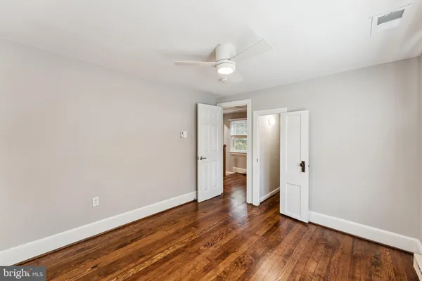an empty room with wooden floor and ceiling fan