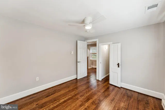 an empty room with wooden floor and ceiling fan