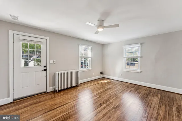 a view of an empty room with wooden floor and a window