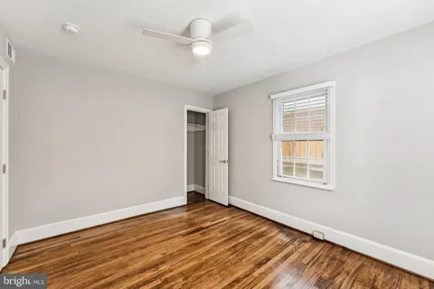 an empty room with wooden floor fan and windows