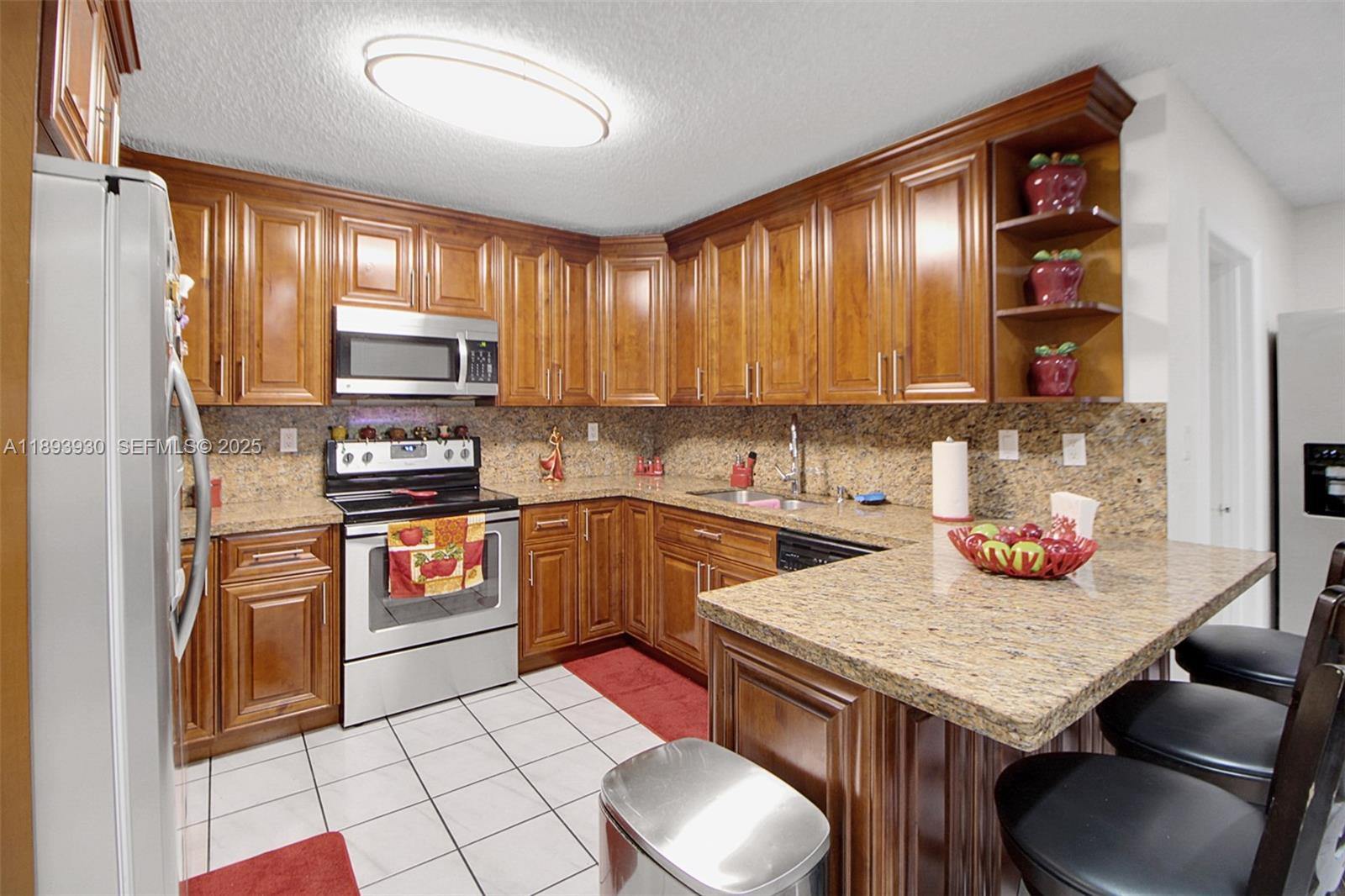 13246 Southwest 9th Terrace Miami, FL 33184 - Photo 4 of 34 a kitchen with stainless steel appliances kitchen island granite countertop a refrigerator a stove top oven and a sink