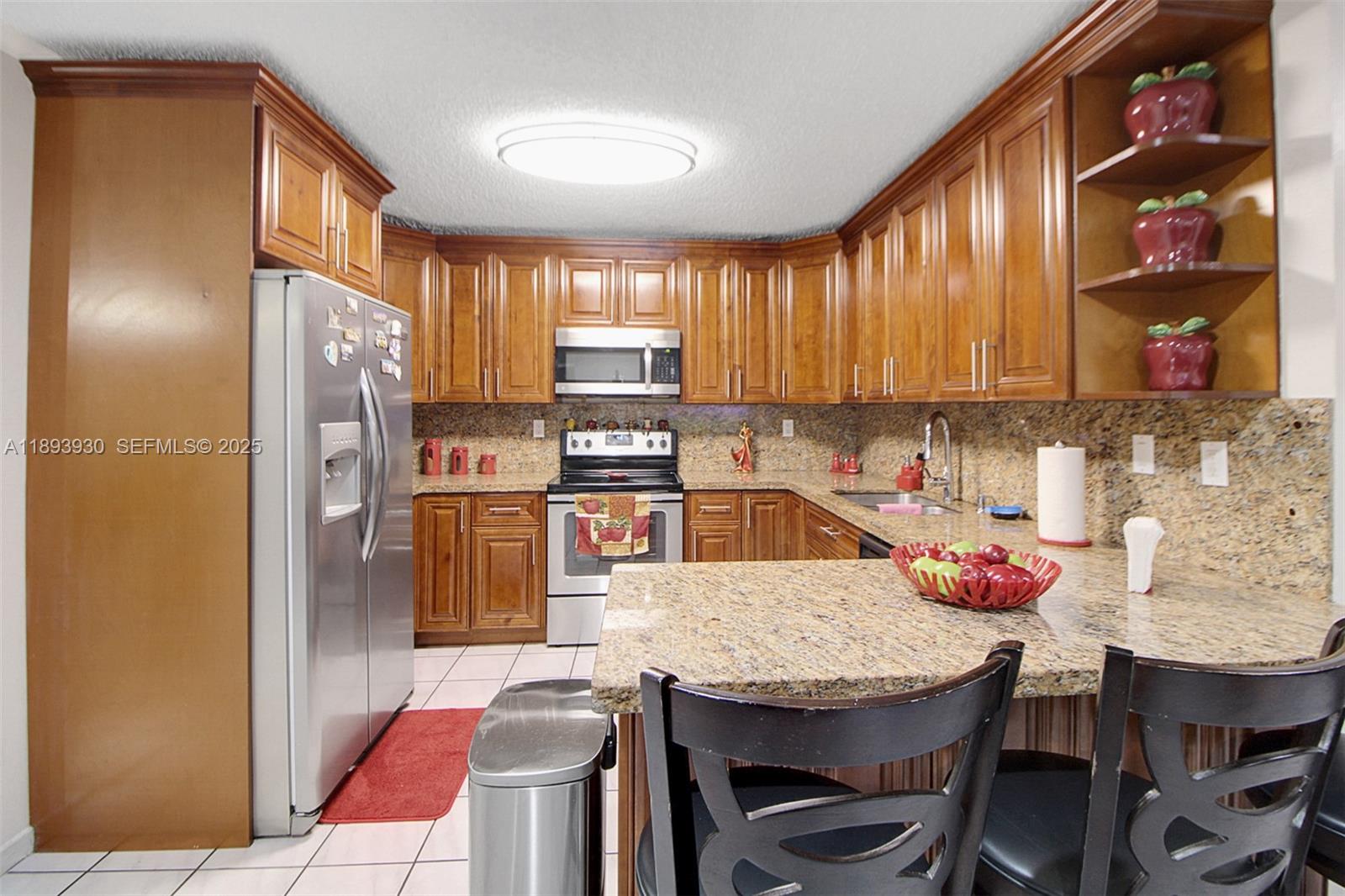 13246 Southwest 9th Terrace Miami, FL 33184 - Photo 5 of 34 a kitchen with granite countertop a table chairs microwave and refrigerator