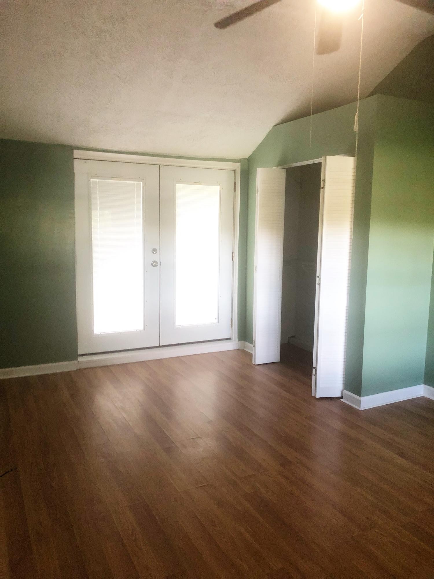 304 Lee Road Clinton, TN 37716 - Photo 13 of 21 an empty room with wooden floor and windows with curtains