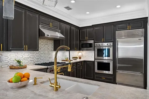 a kitchen with stainless steel appliances kitchen island granite countertop a stove and a sink