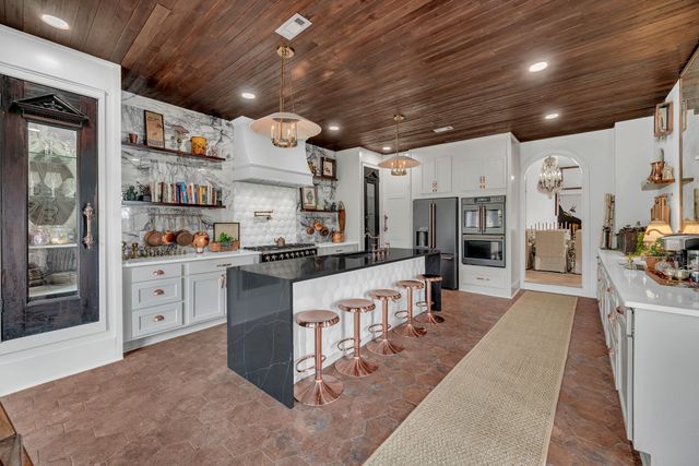 a large white kitchen with lots of counter space and stainless steel appliances